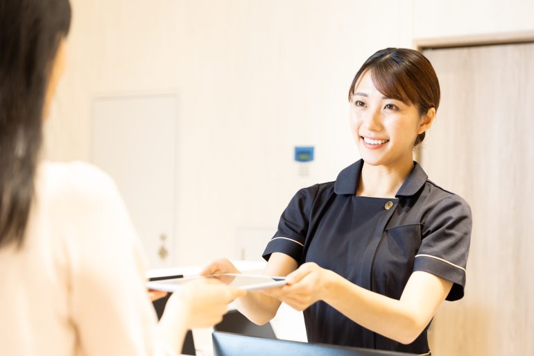 治療について説明するスタッフ（受付でのご案内の様子）